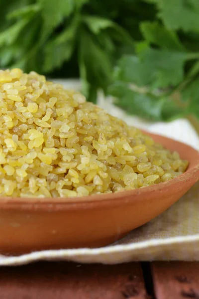 Bulgur in einer Keramikschüssel auf Holztisch — Stockfoto