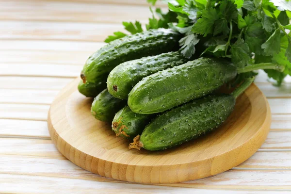 Verse rijpe groene komkommers op een houten tafel — Stockfoto