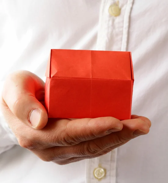 Rotes Origami-Papierhaus in männlicher Hand — Stockfoto
