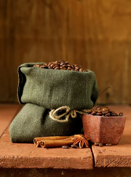 Натюрморт з кавових зерен на полотні мішок на старовинному дерев'яному фоні — стокове фото