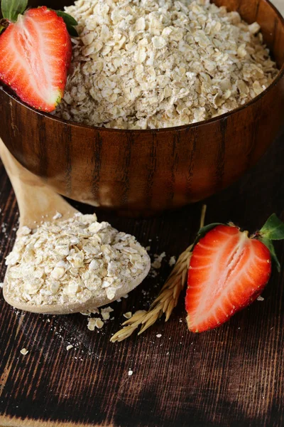 Organic oat flakes with strawberries on a wooden table, a healthy diet — Stock Photo, Image