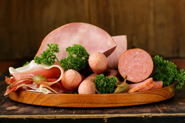Vários tipos de salsichas e bacon defumado na placa de madeira — Fotografia de Stock