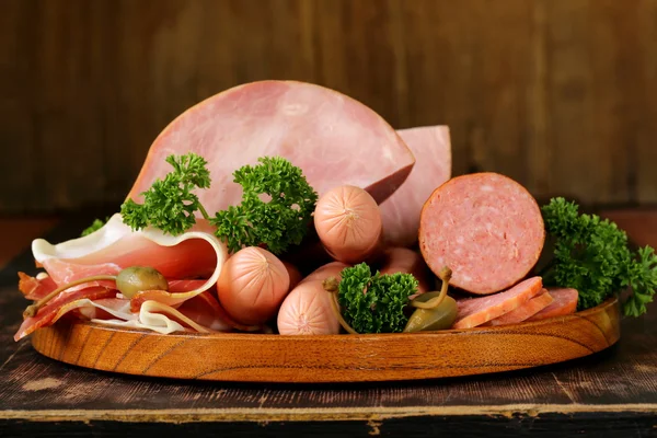 Varios tipos de salchichas y tocino ahumado en el plato de madera —  Fotos de Stock