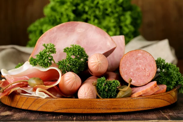 Various kinds of sausages and smoked bacon on the wooden plate Stock Image