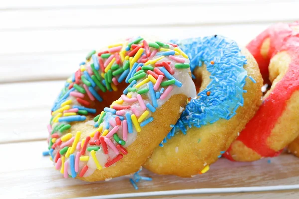 Donuts con esmalte de colores en el fondo de madera — Foto de Stock