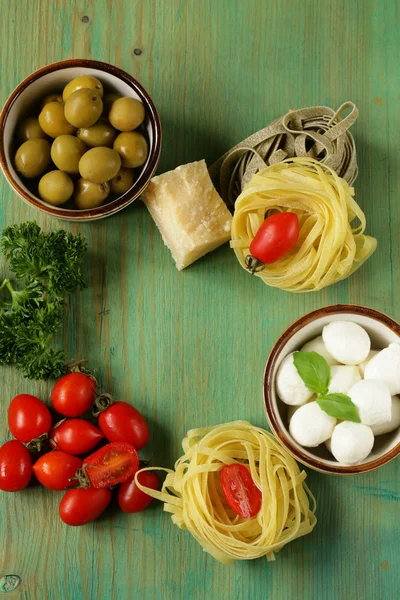 Italian still life - olives, mozzarella cheese, pasta, tomatoes — Stock Photo, Image