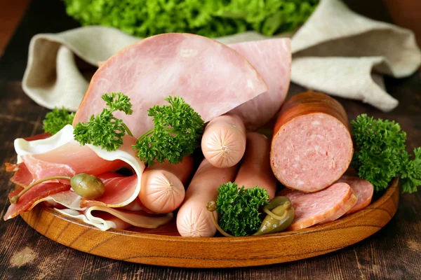 Vários tipos de salsichas e bacon defumado na placa de madeira — Fotografia de Stock
