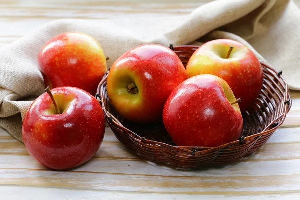 Czerwony dojrzałe jabłka kosz Wiklinowy na drewnianym stołem — Zdjęcie stockowe