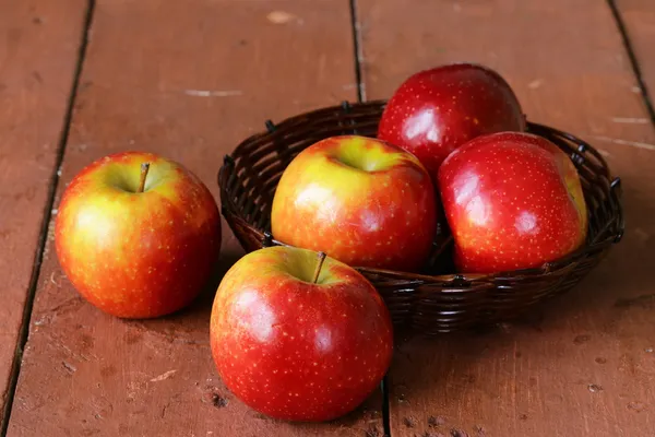 在木制的桌子上的柳条篮子红色熟透了的苹果 — 图库照片