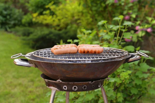 Saucisses rôties sur une grille barbecue en plein air pique-nique — Photo