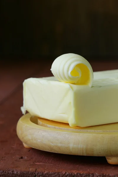 Manteiga amarela fresca servida numa tábua de madeira — Fotografia de Stock