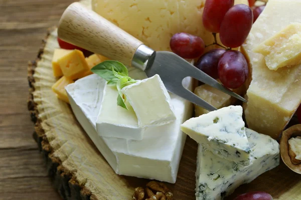 Cheeseboard with assorted cheeses (parmesan, brie, blue, cheddar) — Stock Photo, Image