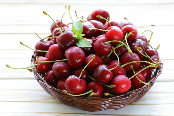 Fresh red ripe cherries in wicker basket on a wooden table — Stock Photo, Image