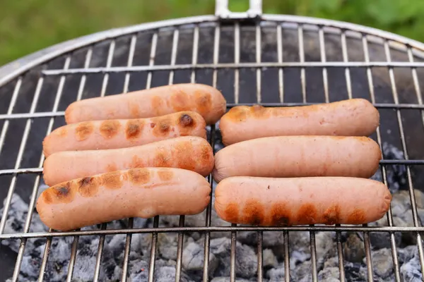 Saucisses rôties sur une grille barbecue en plein air pique-nique — Photo