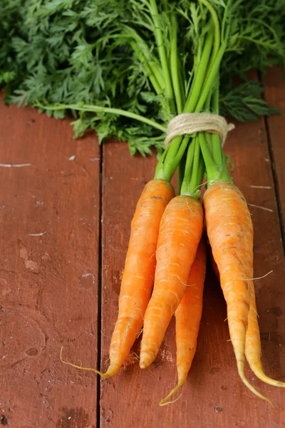 Свіжа органічна морква з зеленим листям на дерев'яному фоні — стокове фото
