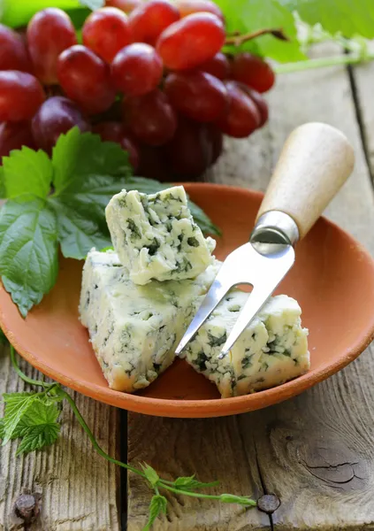 Mavi peynir ile ahşap bir masa üzerinde kırmızı üzüm parçaları — Stok fotoğraf