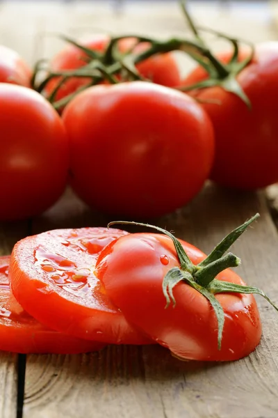 Verse rijpe biologische gesneden tomaten op een houten tafel — Stockfoto