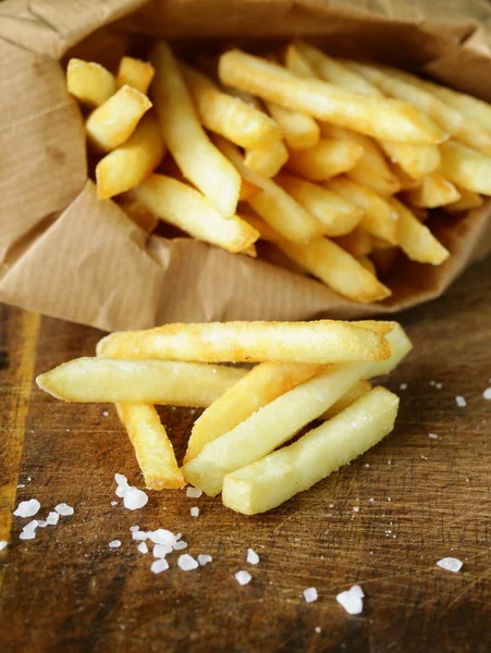 Traditionele aardappelen Franse frietjes met zout op houten achtergrond — Stockfoto