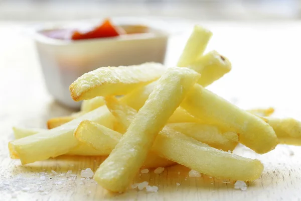 Traditional potatoes French fries with salt on wooden background — Stock Photo, Image