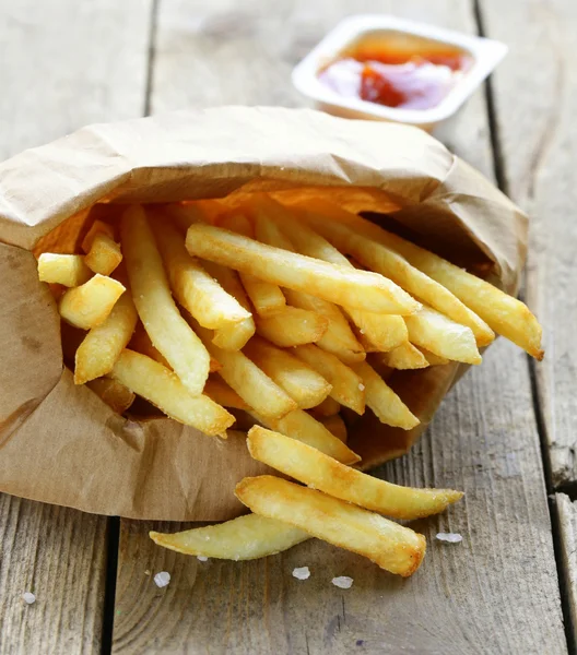 Traditional potatoes French fries with salt on wooden background — Stock Photo, Image