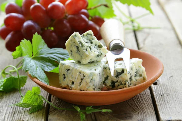 Kousky sýru modré s červenými hrozny na dřevěný stůl — Stock fotografie