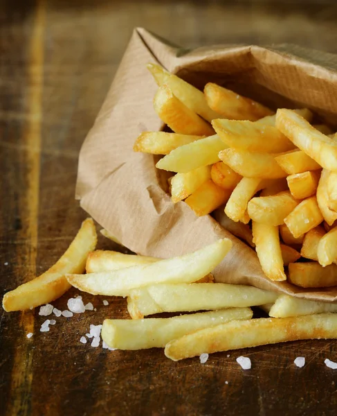 Traditional potatoes French fries with salt on wooden background — Stock Photo, Image