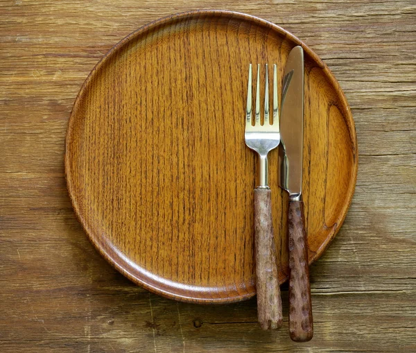 Столовые приборы (нож и вилка) на деревянной тарелке — стоковое фото