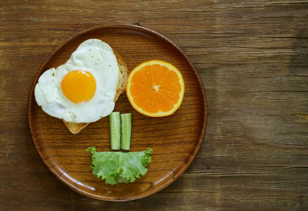 Vicces arc reggelit, tükörtojás, pirítós és zöld saláta — Stock Fotó