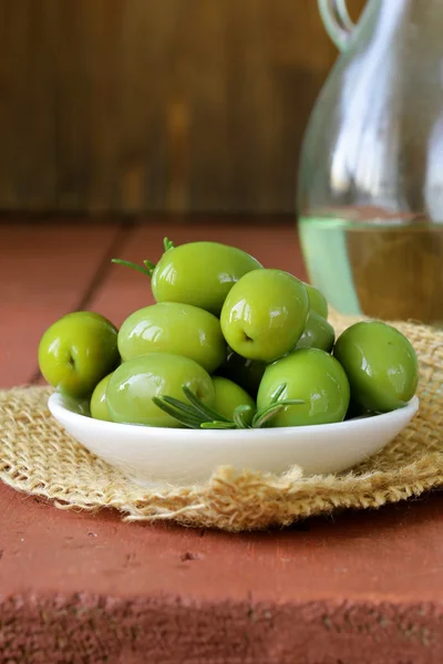 Zielone oliwki marynowane w misce na drewnianym stołem — Zdjęcie stockowe