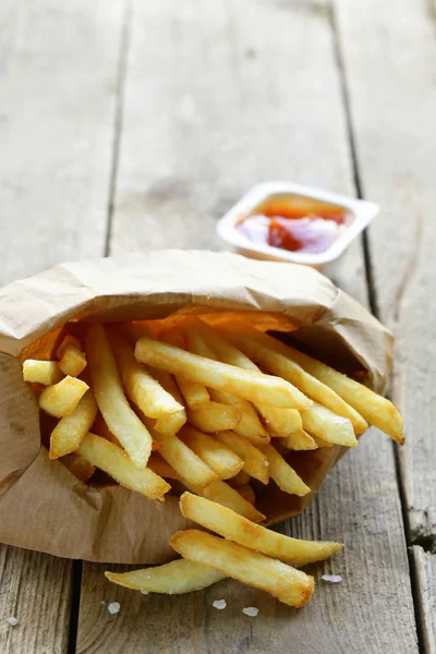 Traditional potatoes French fries with salt on wooden background — Stock Photo, Image