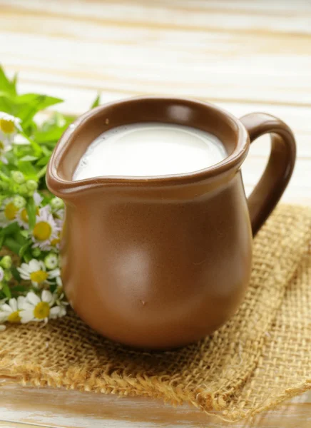 Latte fresco naturale in una brocca di ceramica su un tavolo di legno — Foto Stock