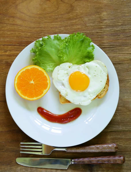 Αστείο πρόσωπο που σερβίρει πρωινό, τηγανητό αυγό, τοστ και πράσινη σαλάτα — Φωτογραφία Αρχείου