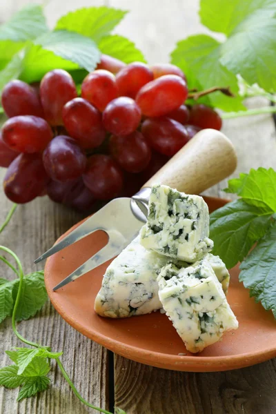 Trozos de queso azul con uvas rojas sobre una mesa de madera —  Fotos de Stock