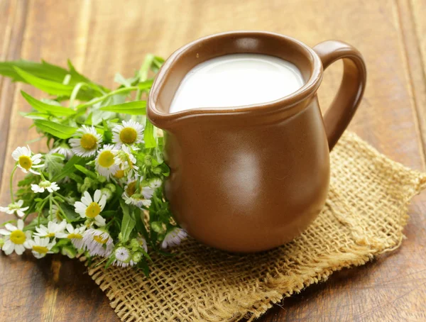 Natuurlijke verse melk in een keramische kruik op een houten tafel — Stockfoto