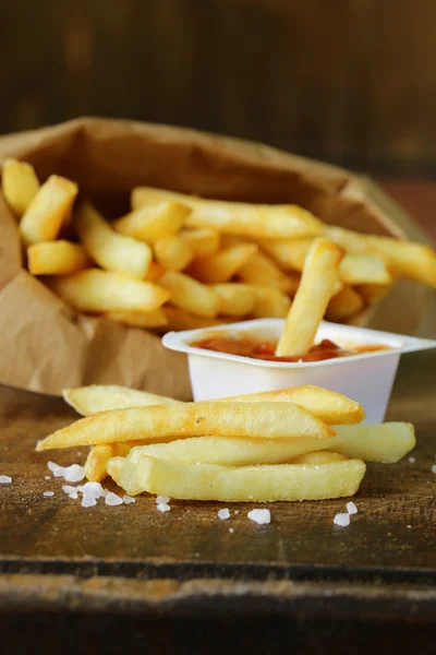 Traditional potatoes French fries with salt on wooden background — Stock Photo, Image