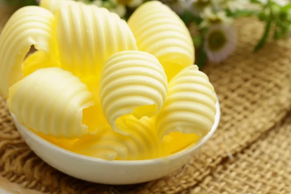 Свежее желтое молочное масло в белой миске — стоковое фото