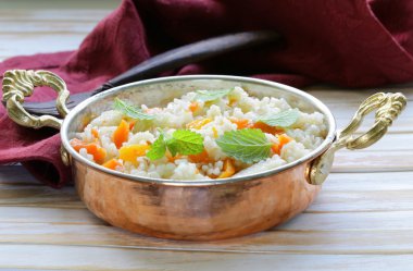 Rice with vegetables cooked in Indian style in a copper pan clipart