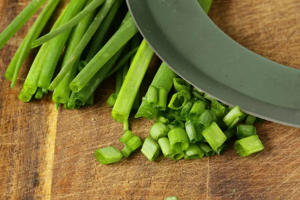 Erba cipollina verde fresca su tavola di legno con un coltello speciale — Foto Stock