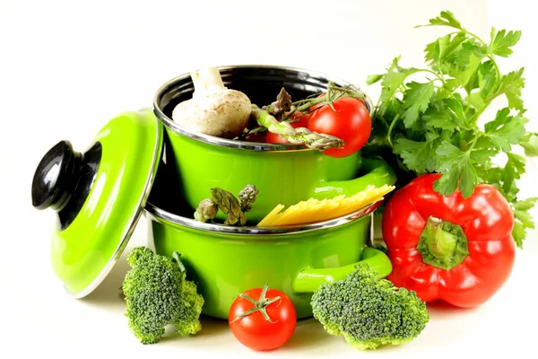 Gröna krukor fulla av grönsaker (tomater, sparris, champinjoner, broccoli) och pasta — Stockfoto
