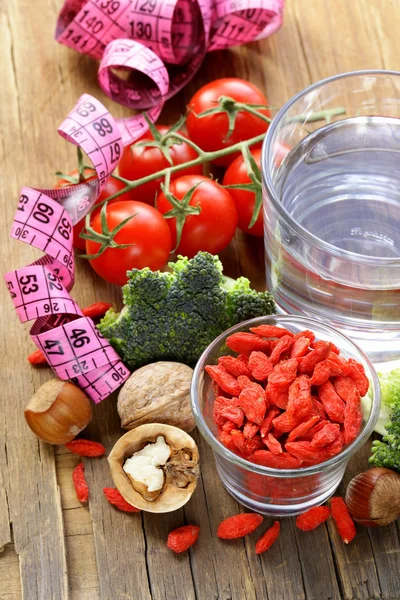 Water, noten, gedroogde goji bessen en verse groenten voor een gezond dieet — Stockfoto