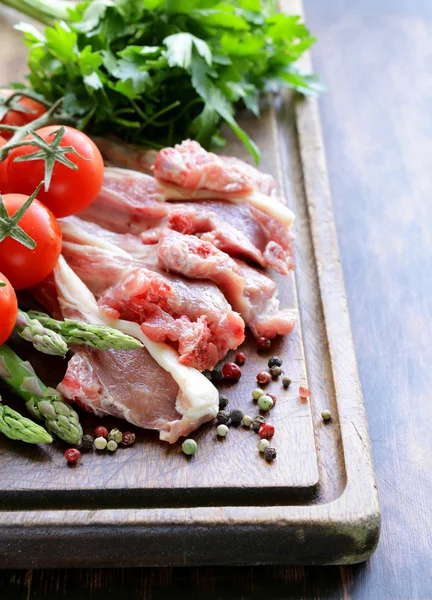 Rått kött, lammkotletter med grönsaker på träskiva — Stockfoto