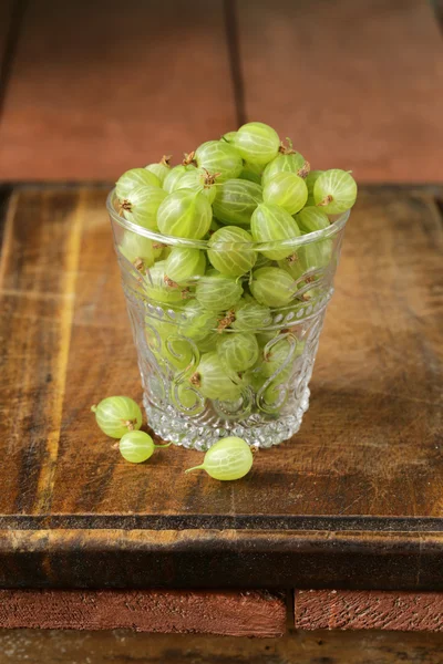 Frescas grosellas verdes maduras sobre mesa de madera —  Fotos de Stock