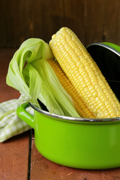 Ripe yellow corn and green pan on a wooden background — Stock Photo, Image