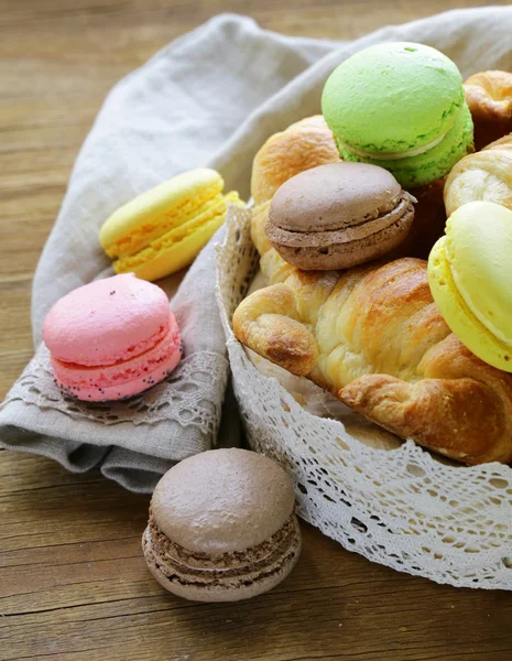 Doces franceses tradicionais croissants e macaroons em uma cesta de renda — Fotografia de Stock