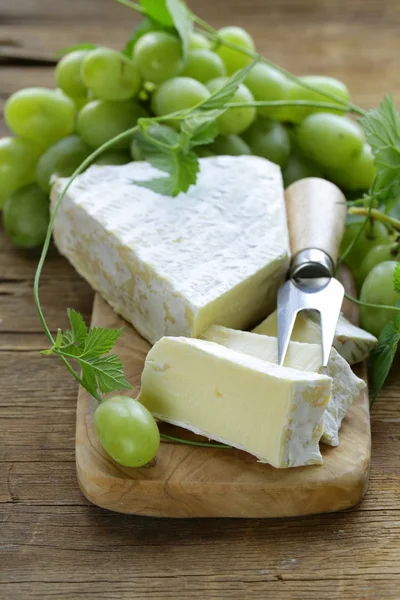 Puha brie sajt, édes szőlő, egy fából készült hajón — Stock Fotó