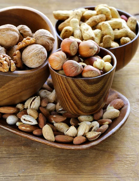 Différents types de noix (amandes, noix, noisettes, arachides) dans un bol sur une table en bois — Photo