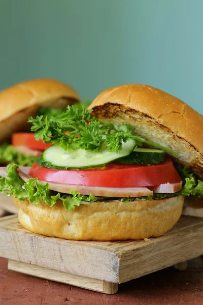 Snack hambúrguer com legumes frescos e presunto em uma tábua de madeira — Fotografia de Stock