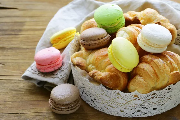 Pasteles tradicionales franceses croissants y macarrones en una canasta de encaje — Foto de Stock