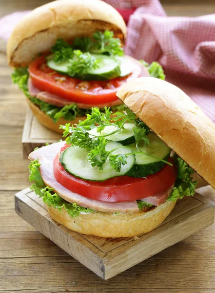 Snack burger with fresh vegetables and ham on a wooden board — Stock Photo, Image