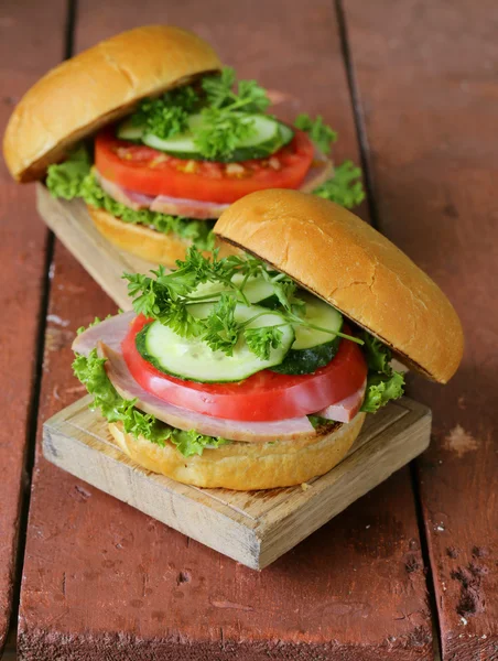 Hamburger snack con verdure fresche e prosciutto su una tavola di legno — Foto Stock